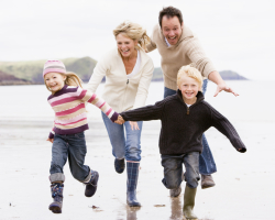 Family running on beach holding hands smiling