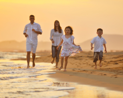 Happy young family have fun on beach at sunset